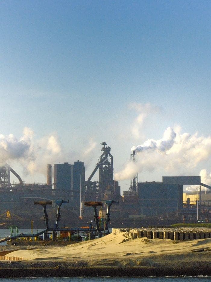 Steelworks emitting smoke against a blue sky