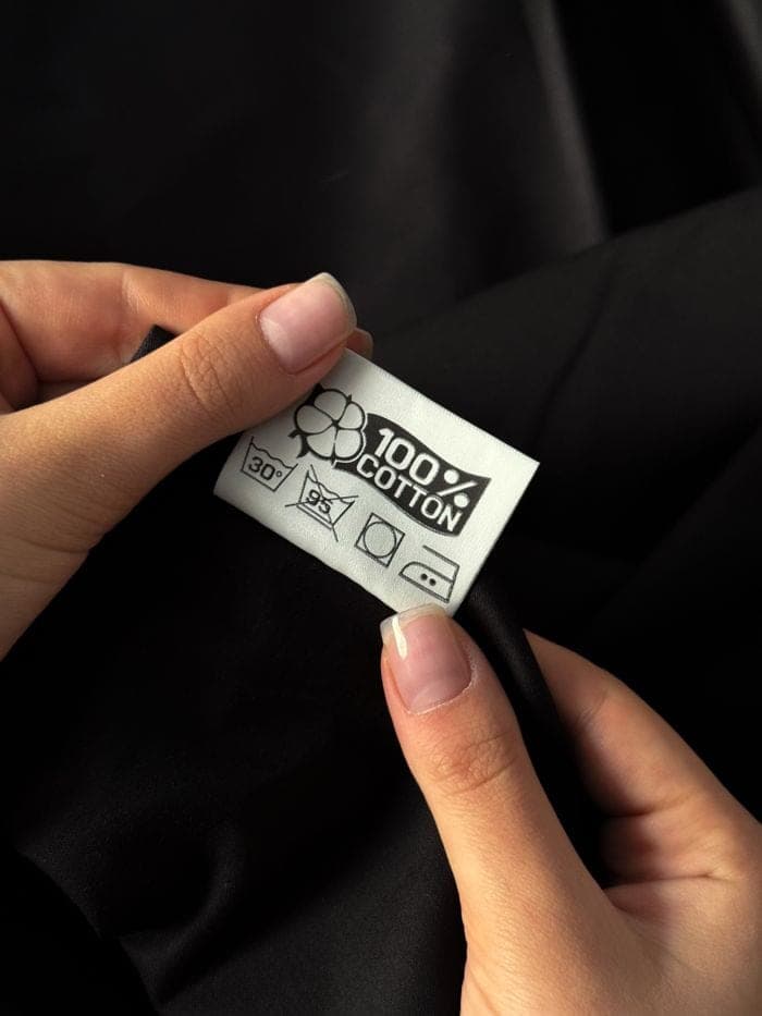 Hands holding a garment's material and care label