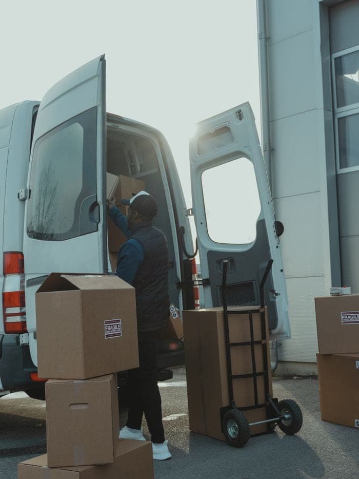 A courier loading parcels into a delivery van