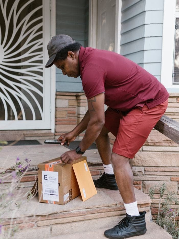 A courier scanning a parcel barcode at a doorstep